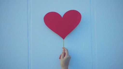 Hand holding a red heart on a stick