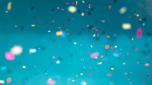 Colorful confetti falling down with a teal background