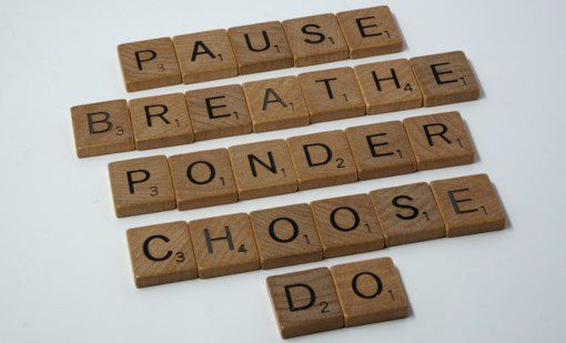 The words pause, breathe, ponder, choose & do spelt out in wooden Scrabble tiles