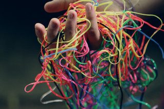 Person holding up tangled multi-coloured tape