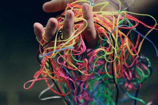 Person holding up tangled multi-coloured tape